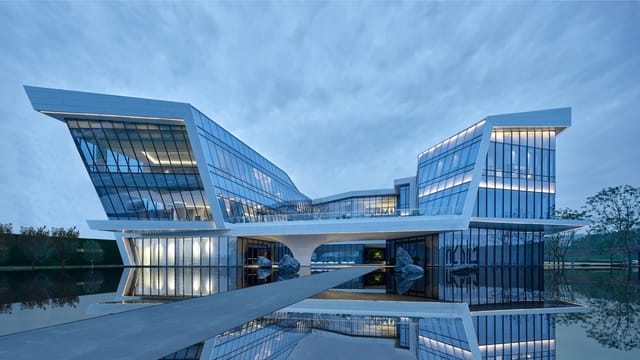 Modern architectural marvel with reflective glass panels by a water body during daytime.