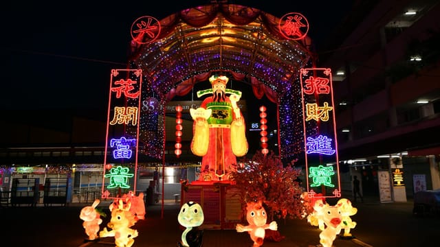 Colorful Chinese New Year decoration with vibrant neon lights and traditional symbols in a street festival setting.