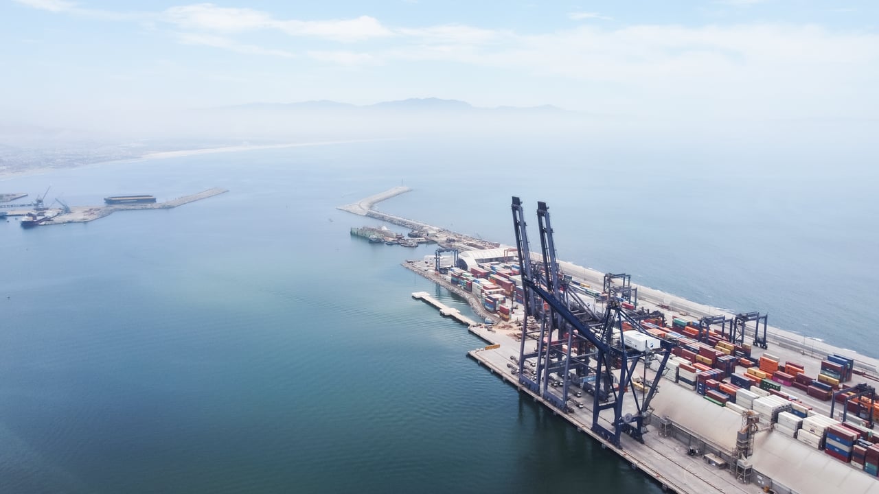 A sweeping aerial shot capturing logistics and container ships at Ensenada Port, Baja California.