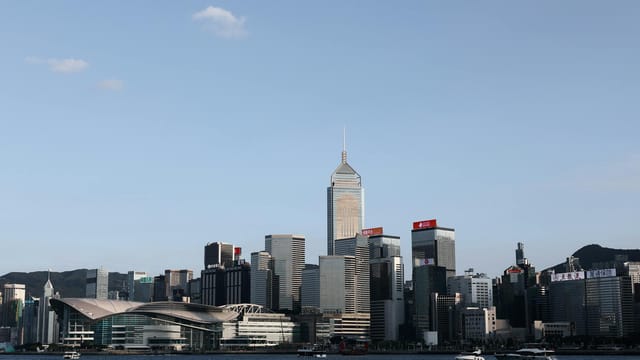 A beautiful view of Hong Kong's skyline and Victoria Harbour during the day with clear skies.