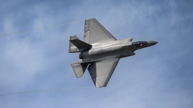 Aerial view of an F-35 fighter jet soaring in a clear blue sky above Kernville, California.