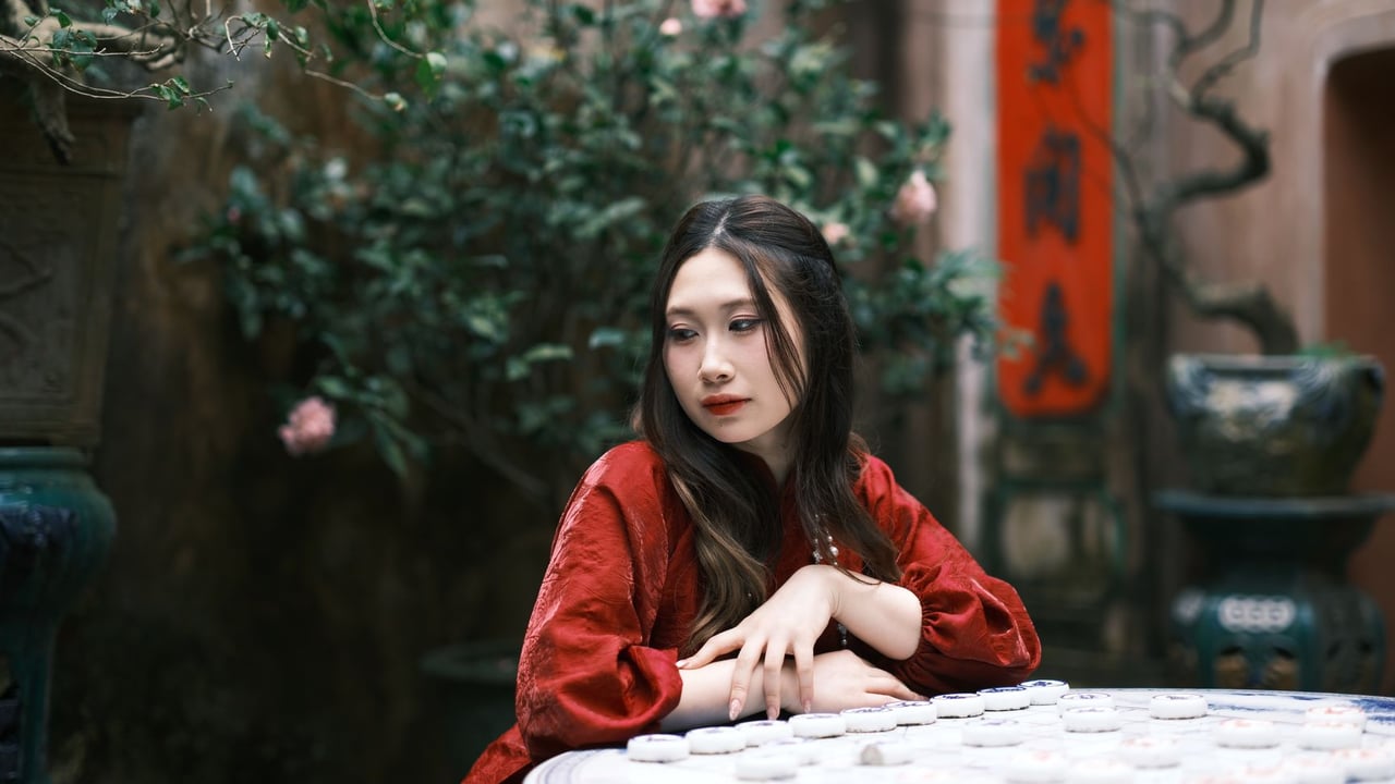 A thoughtful woman in a traditional red dress plays a strategic Chinese game outdoors, surrounded by lush greenery.