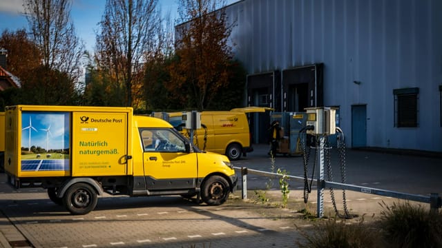 Deutsche Post electric delivery vans parked outdoors emphasizing sustainable logistics.