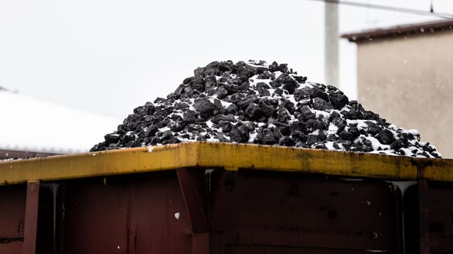 A heap of coal on a freight train car covered with snow, symbolizing transport and industry.