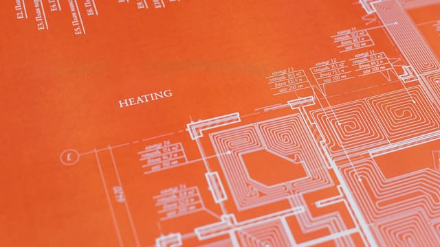 Close-up of an orange architectural heating blueprint showing intricate design details.