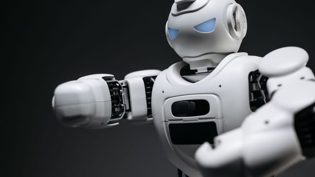 Detailed close-up of a high-tech white robot in a studio setting with a gray background.