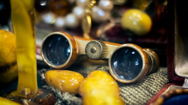 Close-up of elegant vintage opera glasses surrounded by amber stones in Istanbul market.