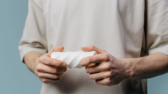 A close-up image of hands holding a white textured cylindrical object indoors.