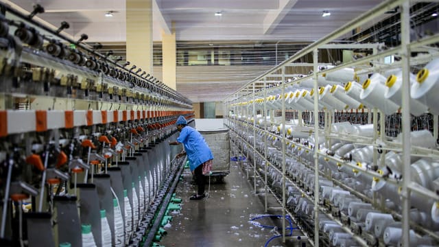 A textile worker handling machinery in a modern factory setting.