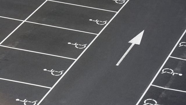 A clean parking lot featuring multiple handicapped spaces and a directional arrow marking.