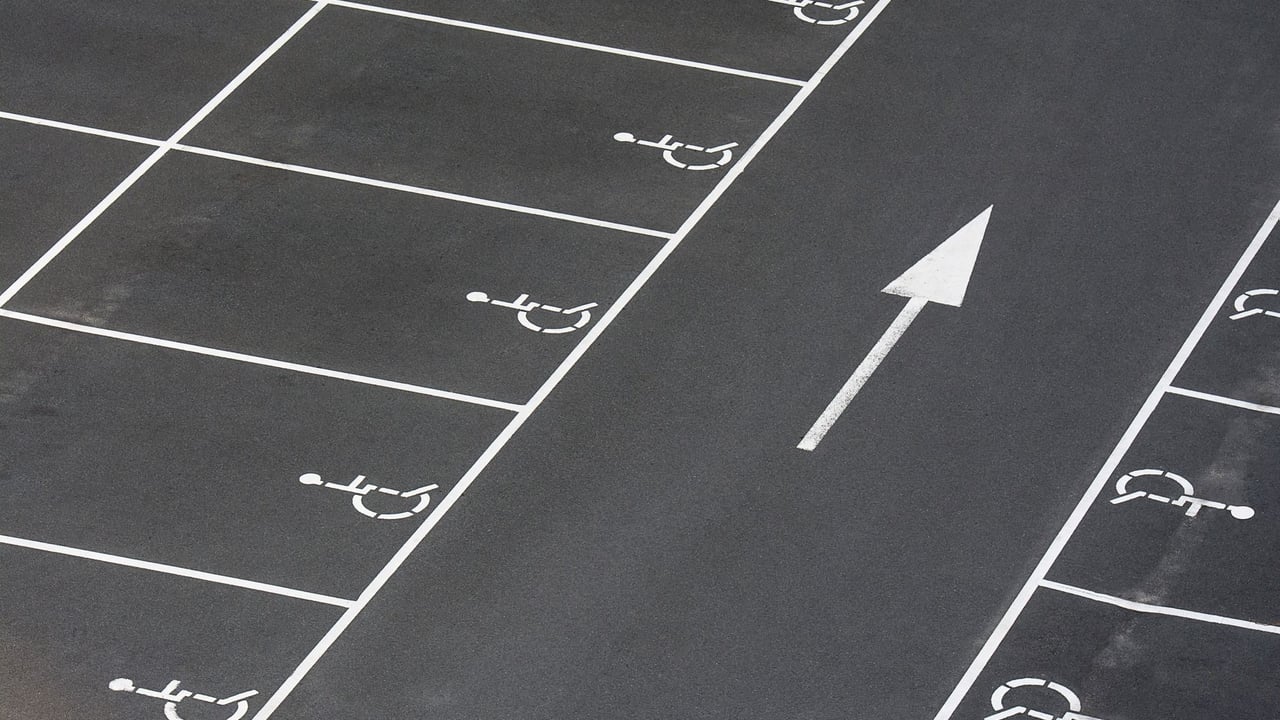 A clean parking lot featuring multiple handicapped spaces and a directional arrow marking.