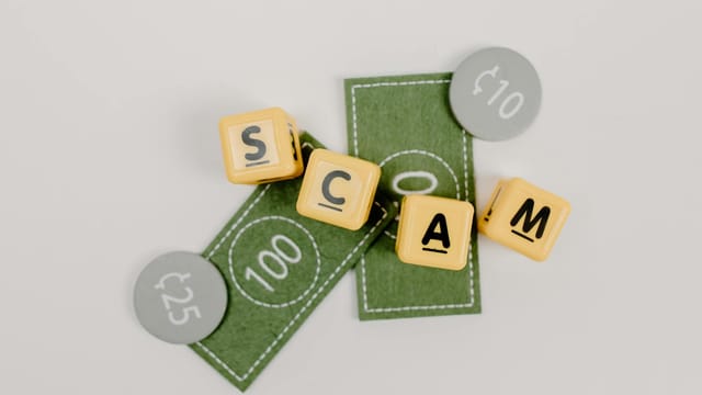 Yellow dice spelling 'Scam' on fake currency, representing financial deception.
