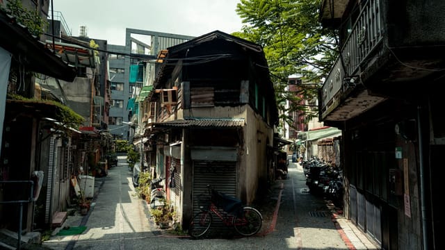 Charming alley in Taipei, Taiwan with vintage bikes, plants, and traditional architecture.