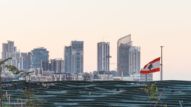Captured view of Beirut's skyline with the Lebanese flag during sunset, showcasing urban architecture.