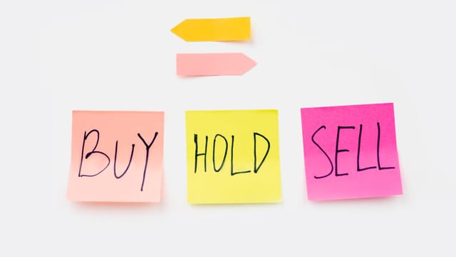 Colorful sticky notes with financial terms 'Buy', 'Hold', and 'Sell' on a clean white backdrop.