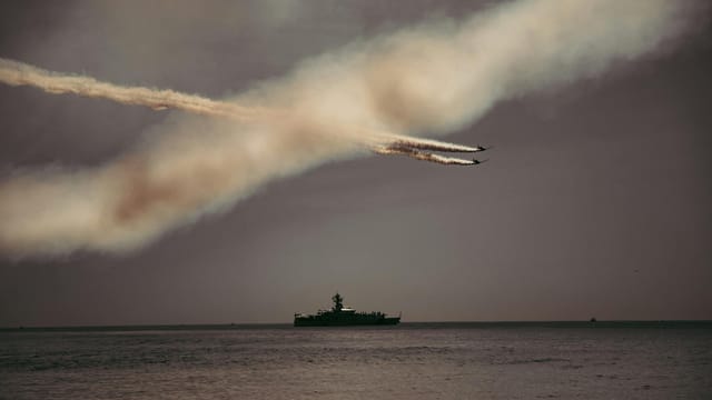 Spectacular airshow in New York Harbor with fighter jets and a ship.