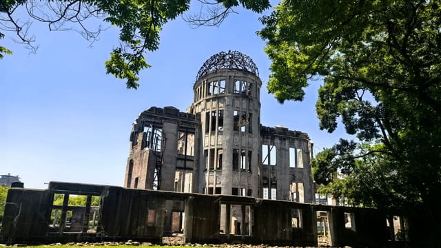 Historic A-Bomb Dome in Hiroshima, symbolizing peace and remembrance amidst lush greenery.
