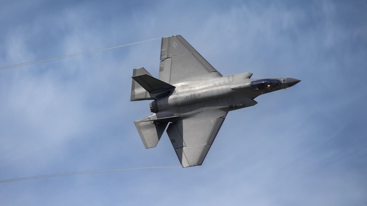 Aerial view of an F-35 fighter jet soaring in a clear blue sky above Kernville, California.