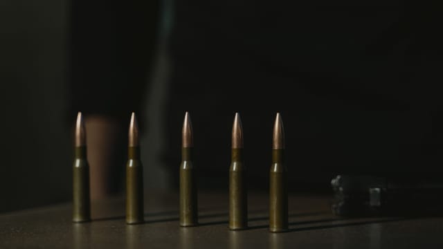 Close-up shot of a row of bullets on a dark surface, emphasizing their metallic texture.