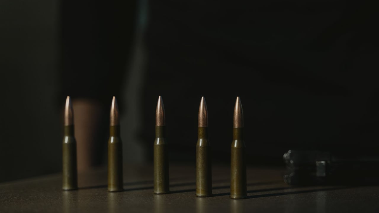 Close-up shot of a row of bullets on a dark surface, emphasizing their metallic texture.