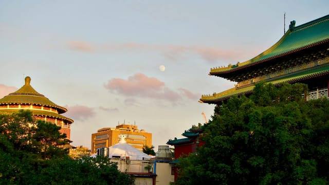 Dramatic sunset over traditional architecture in Taipei City, Taiwan with the moon rising.