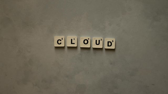 Scrabble tiles arranged to spell 'cloud' on a neutral textured backdrop, creative concept image.