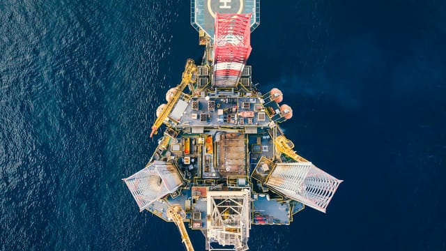 High-angle view of an offshore oil platform with helipad surrounded by deep blue ocean.
