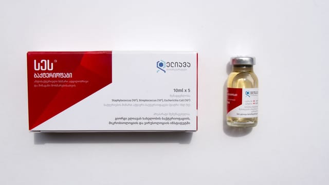 Close-up of medication vial and box with Georgian text on white surface.
