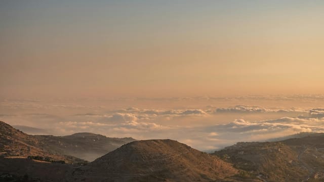 Stunning aerial view of Faraiya, Lebanon, showcasing a sea of clouds over mountains during sunrise.