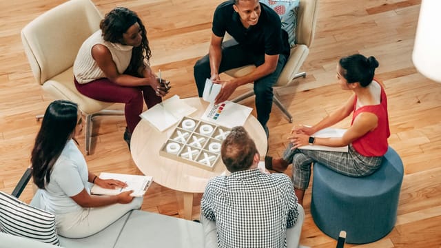 A group of diverse coworkers engaged in a collaborative meeting in a modern indoor office setting.