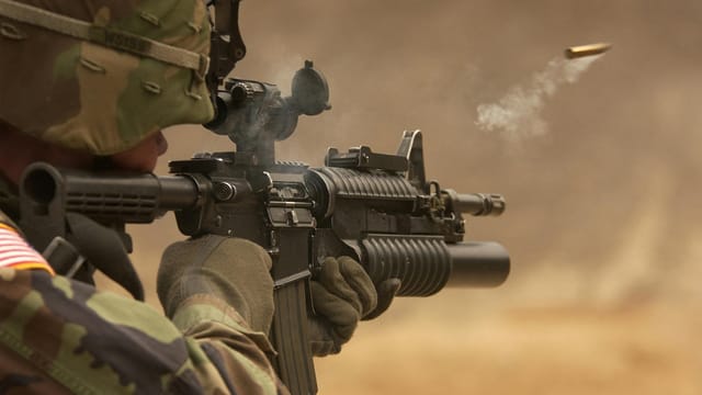 Close-up of a soldier in camo firing a rifle in action during training.