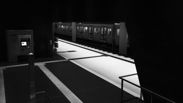 Black and white photo of an empty Berlin subway station, capturing an urban and moody atmosphere.