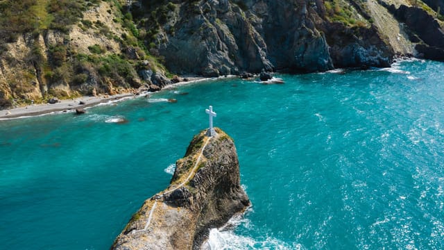 A stunning aerial shot of Cape Fiolent in Sevastopol featuring a coastal cross and turquoise waters.