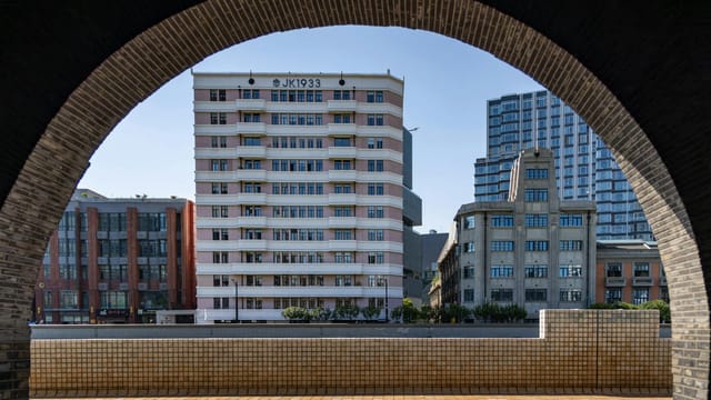 Elegant city buildings seen through a curved brick arch in daylight.