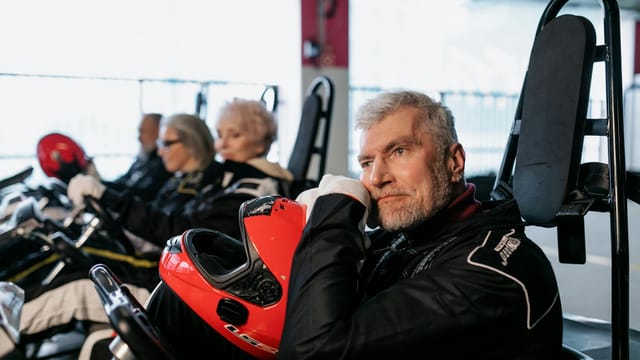 Senior adults in race suits enjoying a day of go-karting indoors.