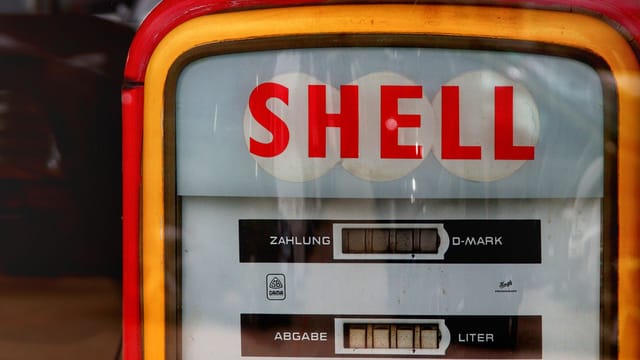 Close-up of a vintage Shell gas pump with classic retro design and German text.