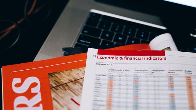Detailed close-up of economic and financial documents on a laptop keyboard, highlighting data analytics.