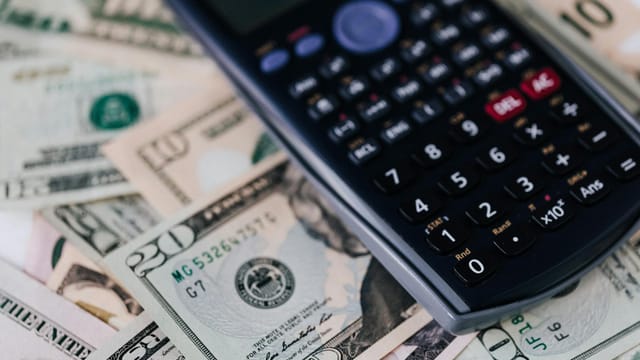 Macro shot of a calculator on US dollar bills, symbolizing finance and budgeting.