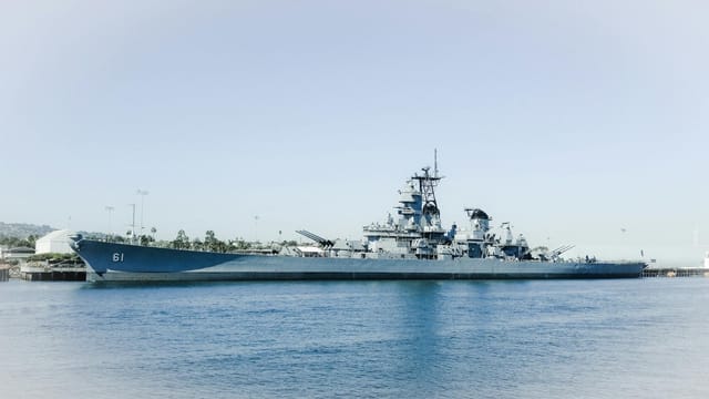 The USS Iowa battleship docked in Los Angeles harbor, California against a clear blue sky.