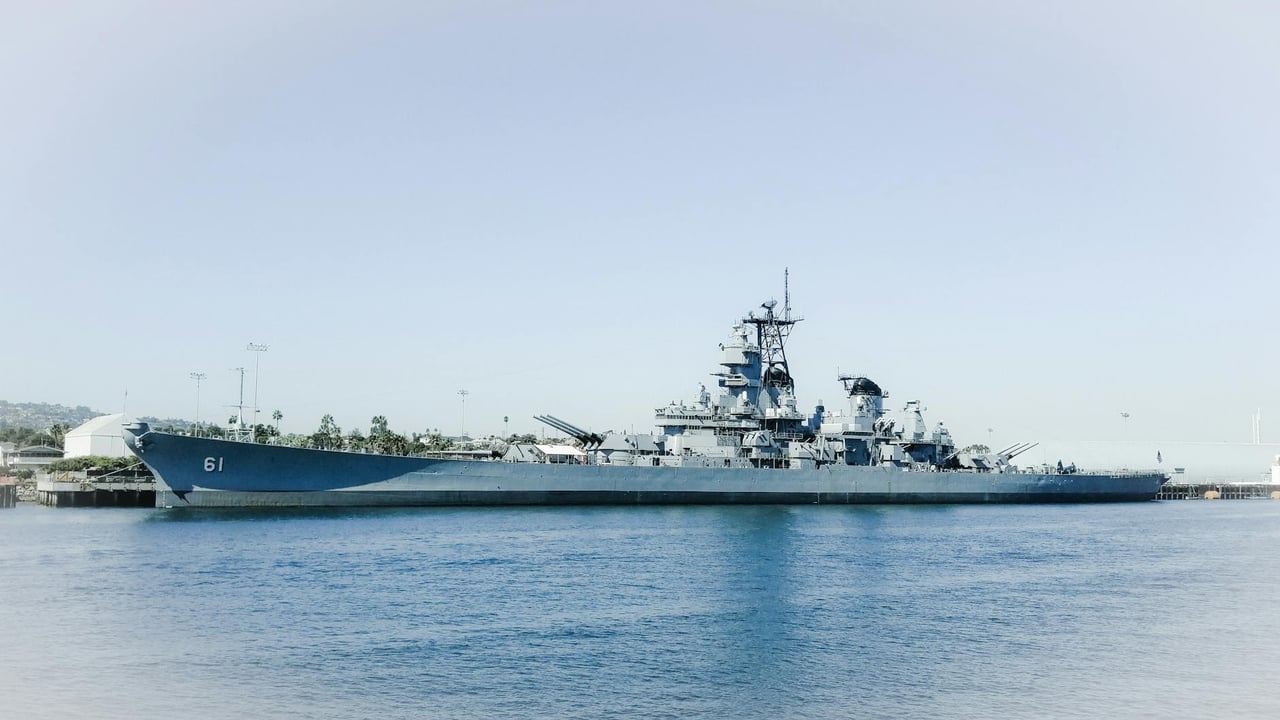 The USS Iowa battleship docked in Los Angeles harbor, California against a clear blue sky.