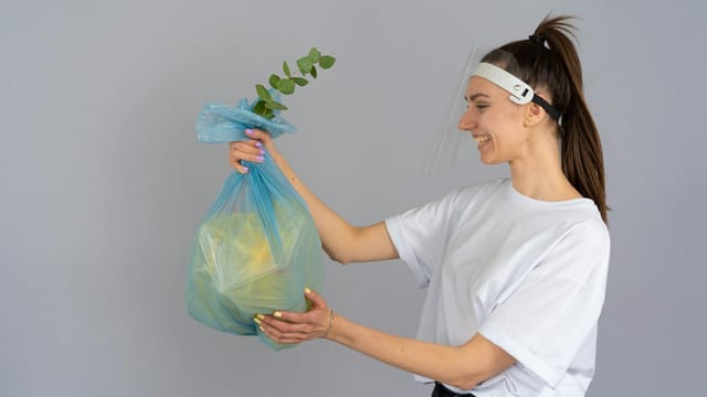 Smiling woman holding a recyclable bag with a plant, promoting eco-friendly practices.