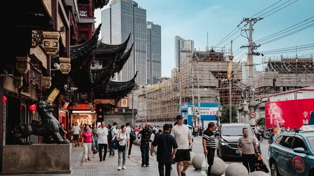 A bustling urban street scene blending modern skyscrapers and traditional Asian architecture.