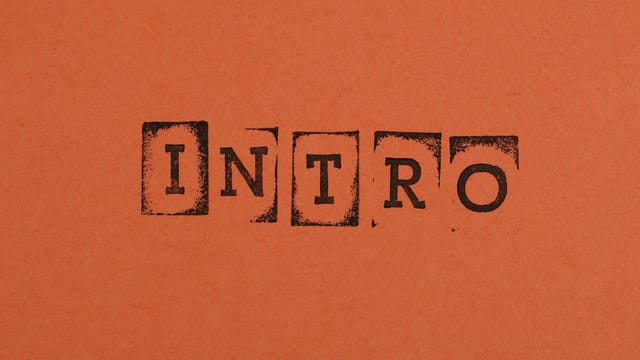 Close-up of the word INTRO stamped in black on an orange background, conveying a bold entrance.