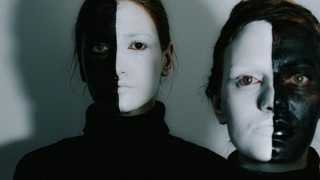 Artistic portrait of two women with dramatic split black and white face paint.