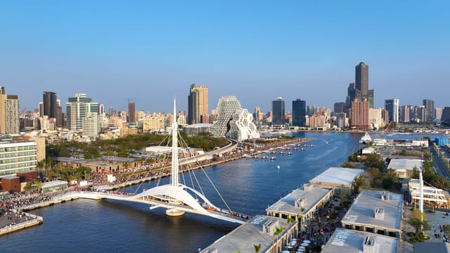 Aerial view of Kaohsiung cityscape and waterfront on a clear day, showcasing modern architecture.