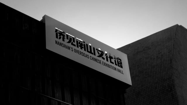 A black and white photo capturing Nanshan's Overseas Chinese Exhibition Hall at dusk.