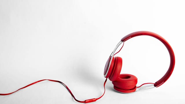 Stylish red over-ear headphones with long cable against a white background.