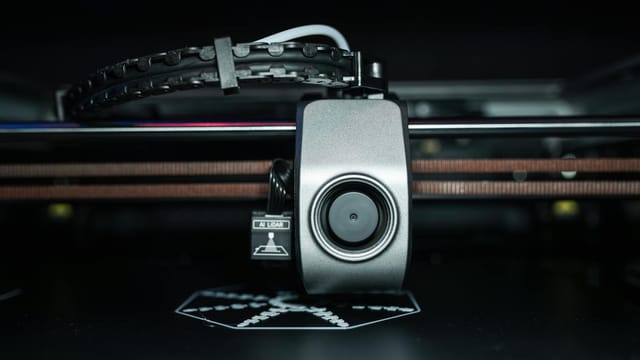 Detailed close-up of a 3D printer extrusion head in focus, showcasing modern technology.