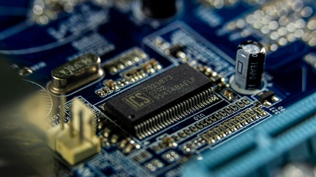Detailed shot of a microprocessor on a blue motherboard showcasing electronic components.