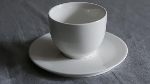 Elegant close-up of a white porcelain cup on a saucer, perfect for tableware or coffee themes.